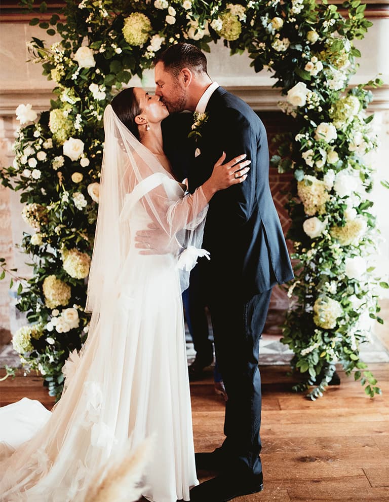 married couple under floral archway