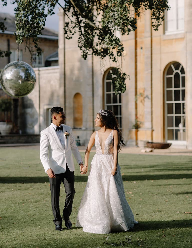 dreamlike bride and groom walk in aynhoe park with disco ball