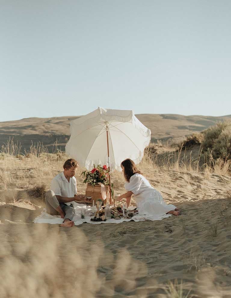 couple having a picnic on sandy beach with gifts
