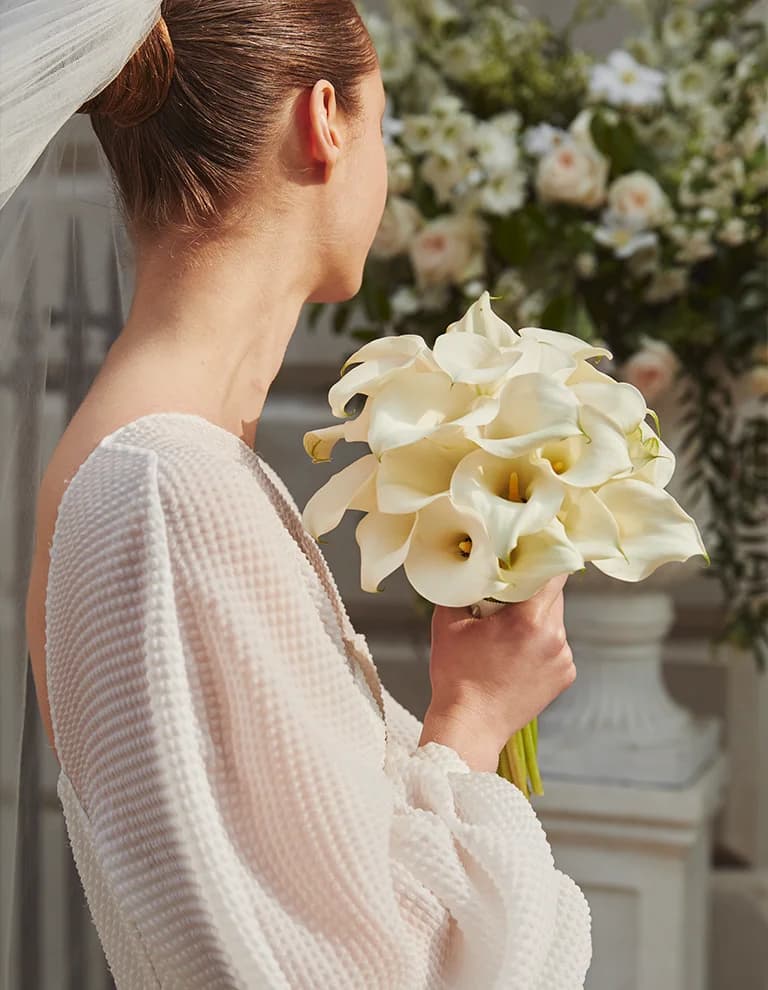bride holds bridal bouquet with calla lilies