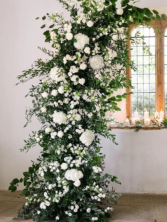 Delicate wedding floral arch with green foliage and white hydrangeas