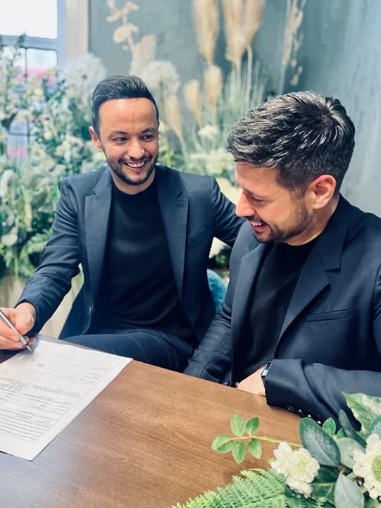 Grooms signing their marriage certificate during registry office wedding