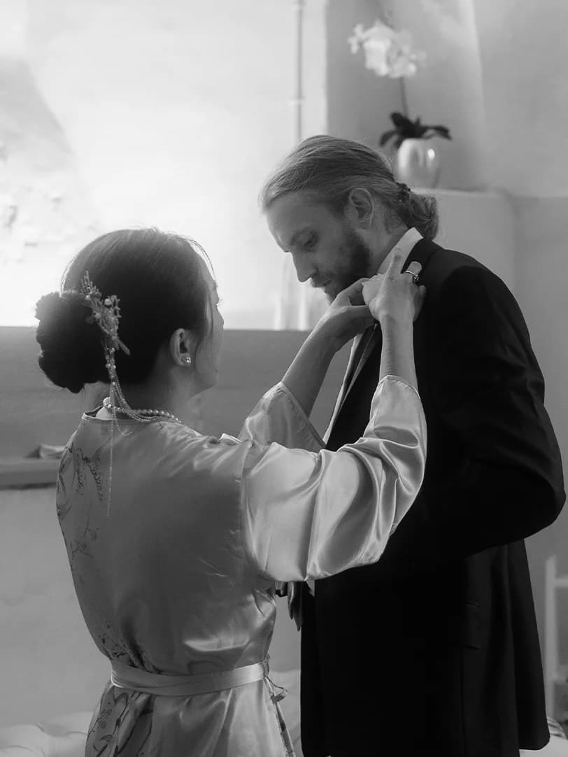 Groom is getting ready with the help from bride