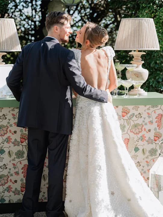 Bride and groom stand next to a beautifully decorated wedding bar