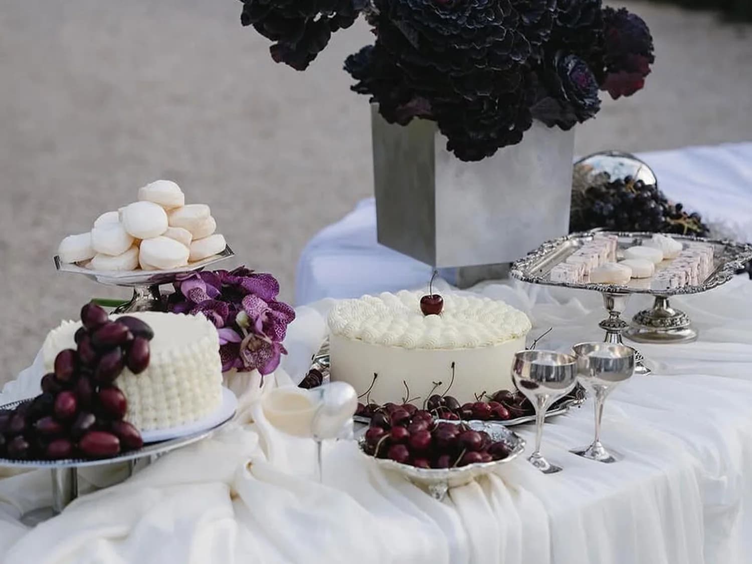 A table with a variety of wedding cakes served among dark flowers