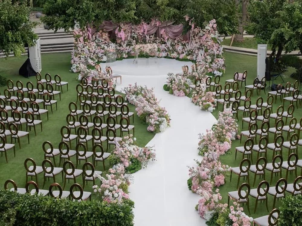 A serpentine wedding aisle decorated with flower arrangements