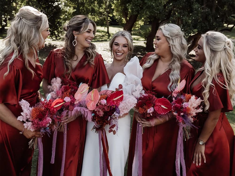Bride surrounded by bridesmaids wearing red bridesmaids dresses