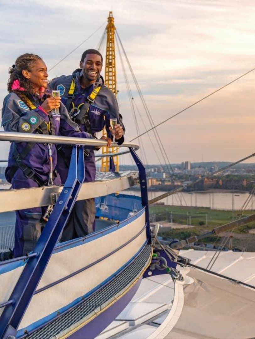 Couple climbs O2 at sunset with champagne in hand