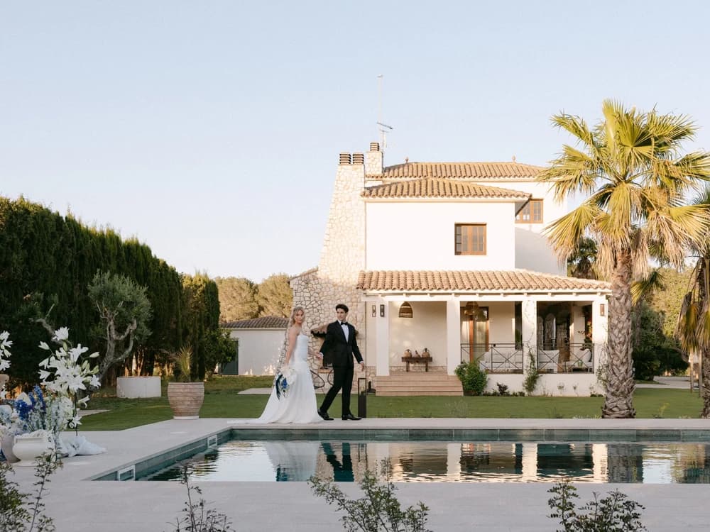 Bride and groom walk in front of a Spanish villa