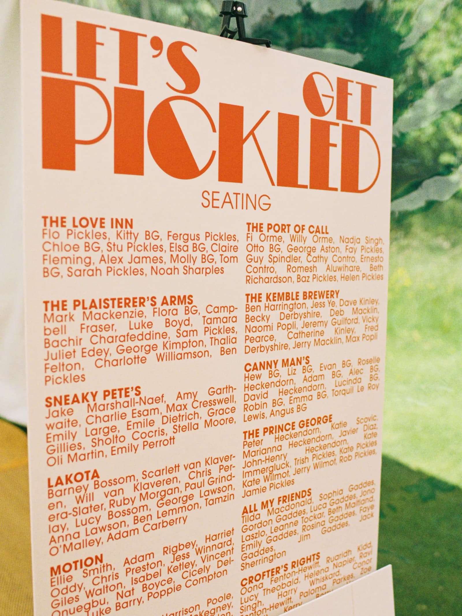 Orange Let's Get Pickled wedding seating plan in the Studio 54 font, with tables named after pubs, at a festival wedding