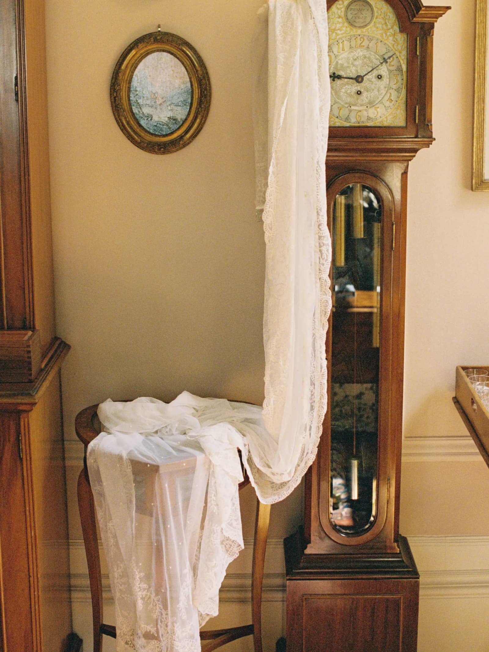 Cathedral-length vintage silk veil from Jane Bourvis hanging beside a grandfather clock at Middleton House in Scotland